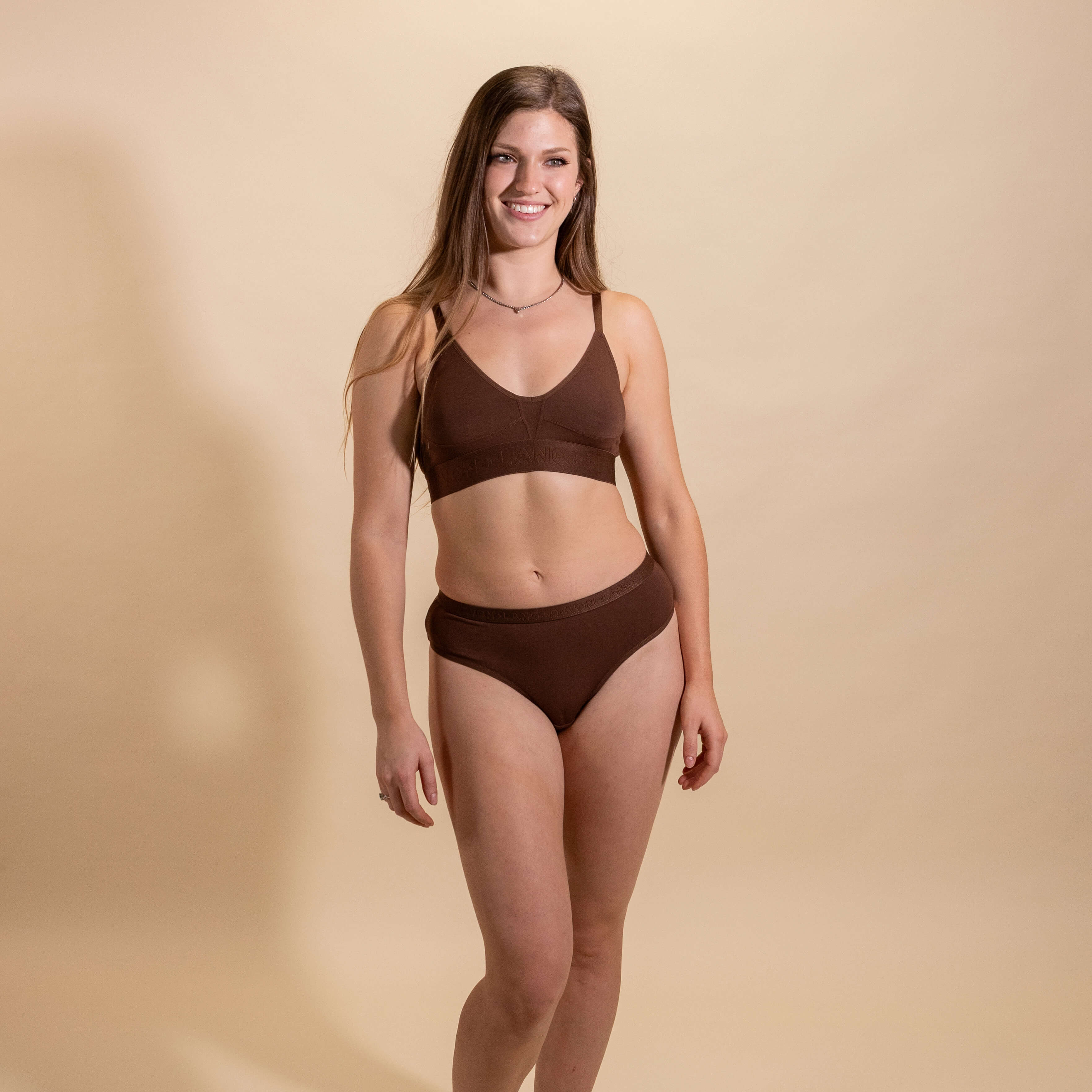 Woman wearing a brown underwear set on a beige background
