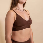Woman wearing a brown bralette against a beige background