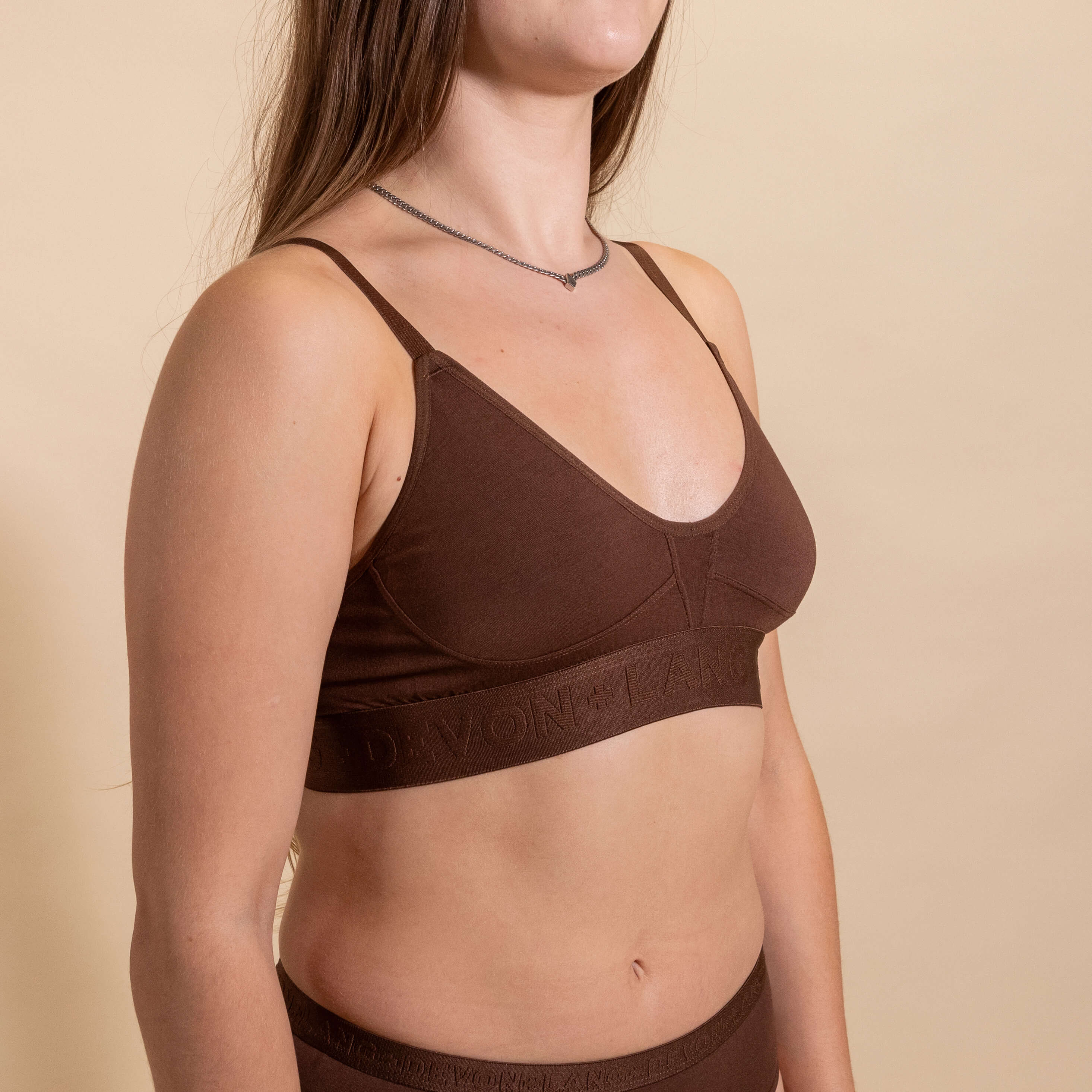 Woman wearing a brown bralette against a beige background