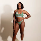 Woman wearing a green patterned underwear set against a plain background