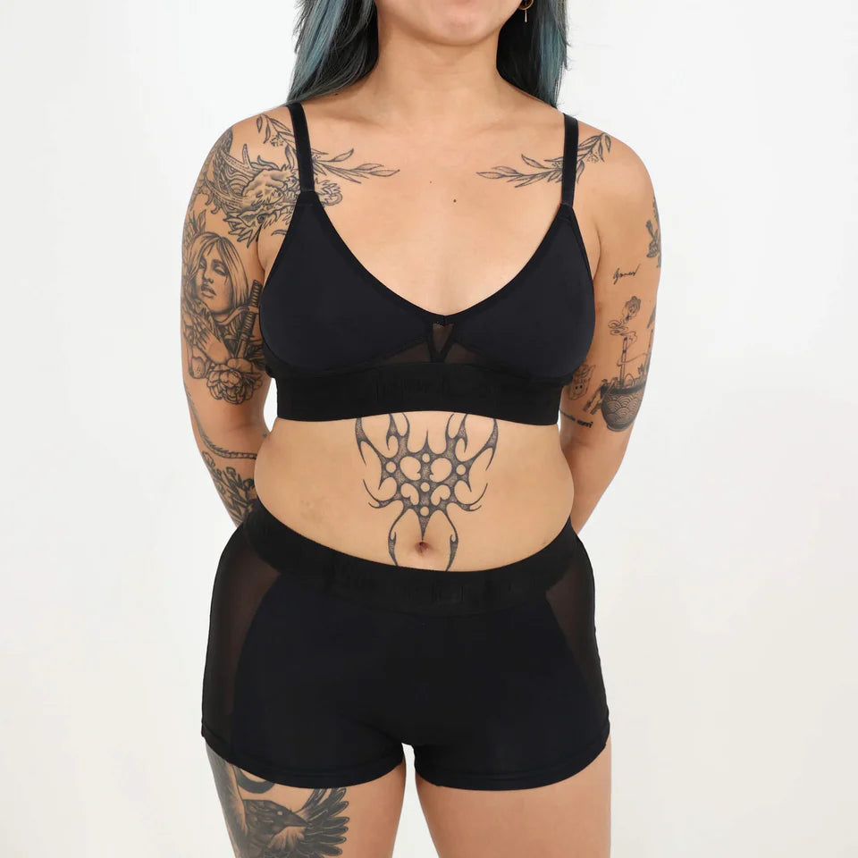 A woman wearing a black bra and shorts set on a white background