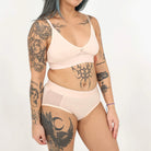 A woman wearing a beige bra and underwear set against a white background