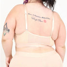 A persona wearing a beige bra and underwear set against a white background