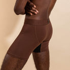 Brown boxer briefs worn by a person on a beige background
