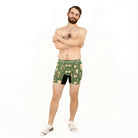 Man wearing green patterned boxer briefs on a white background