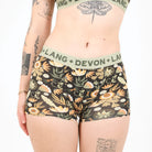 A woman wearing floral boyshort underwear against a white background