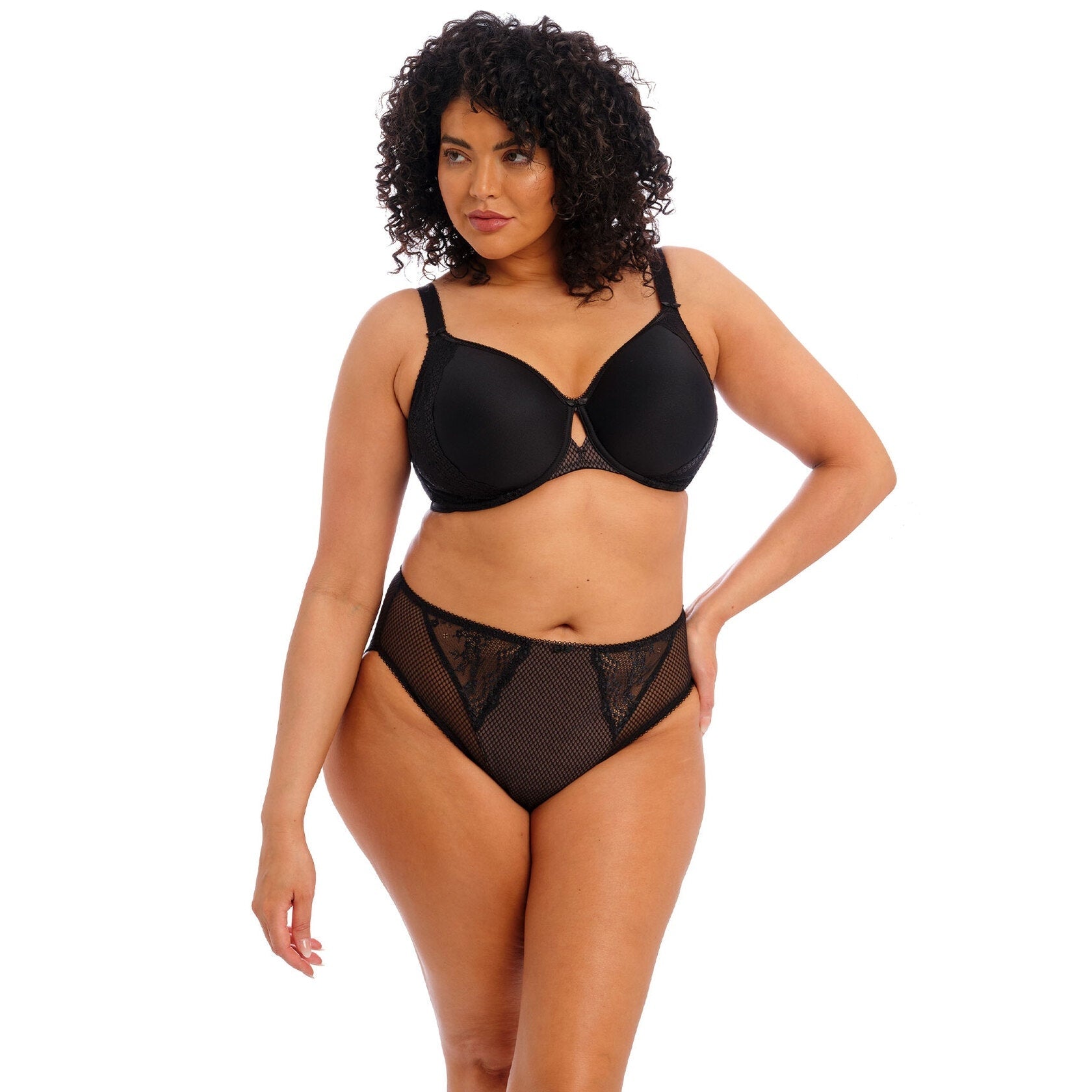 Woman wearing a black bra and panty set with pace details against a white back ground. 