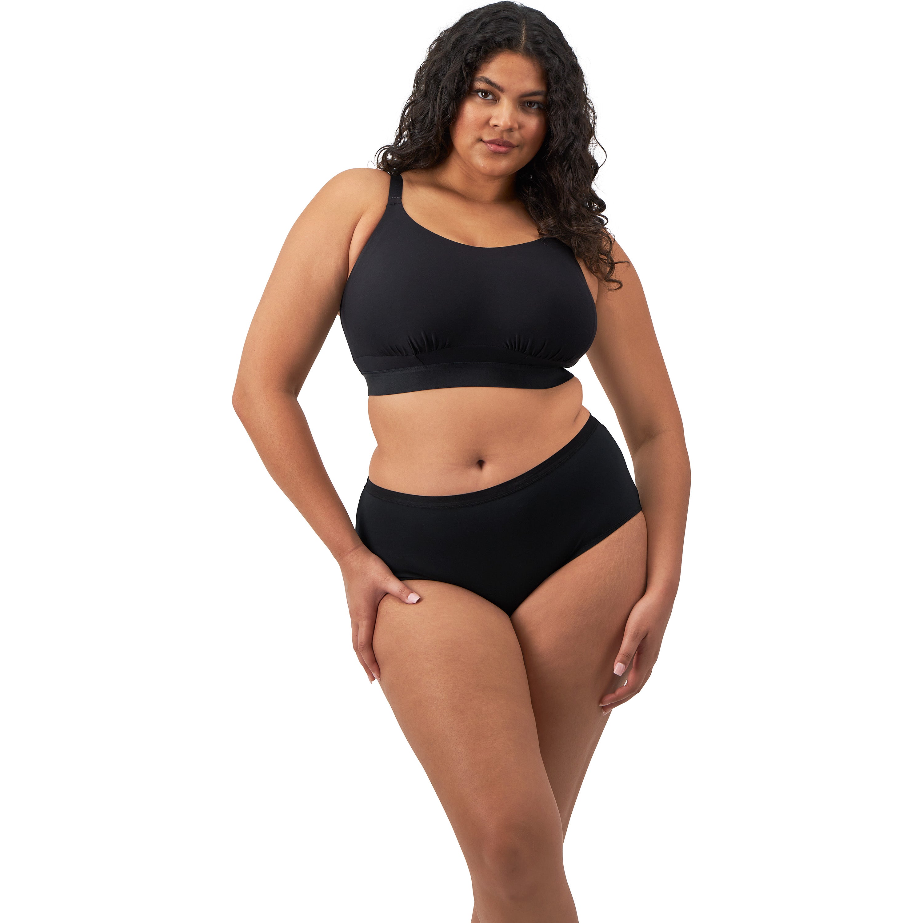 A woman wearing a black wireless bra and panty set against a white back ground. 