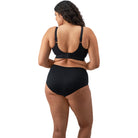 A woman wearing a black bra and panty set against a white back ground. 
