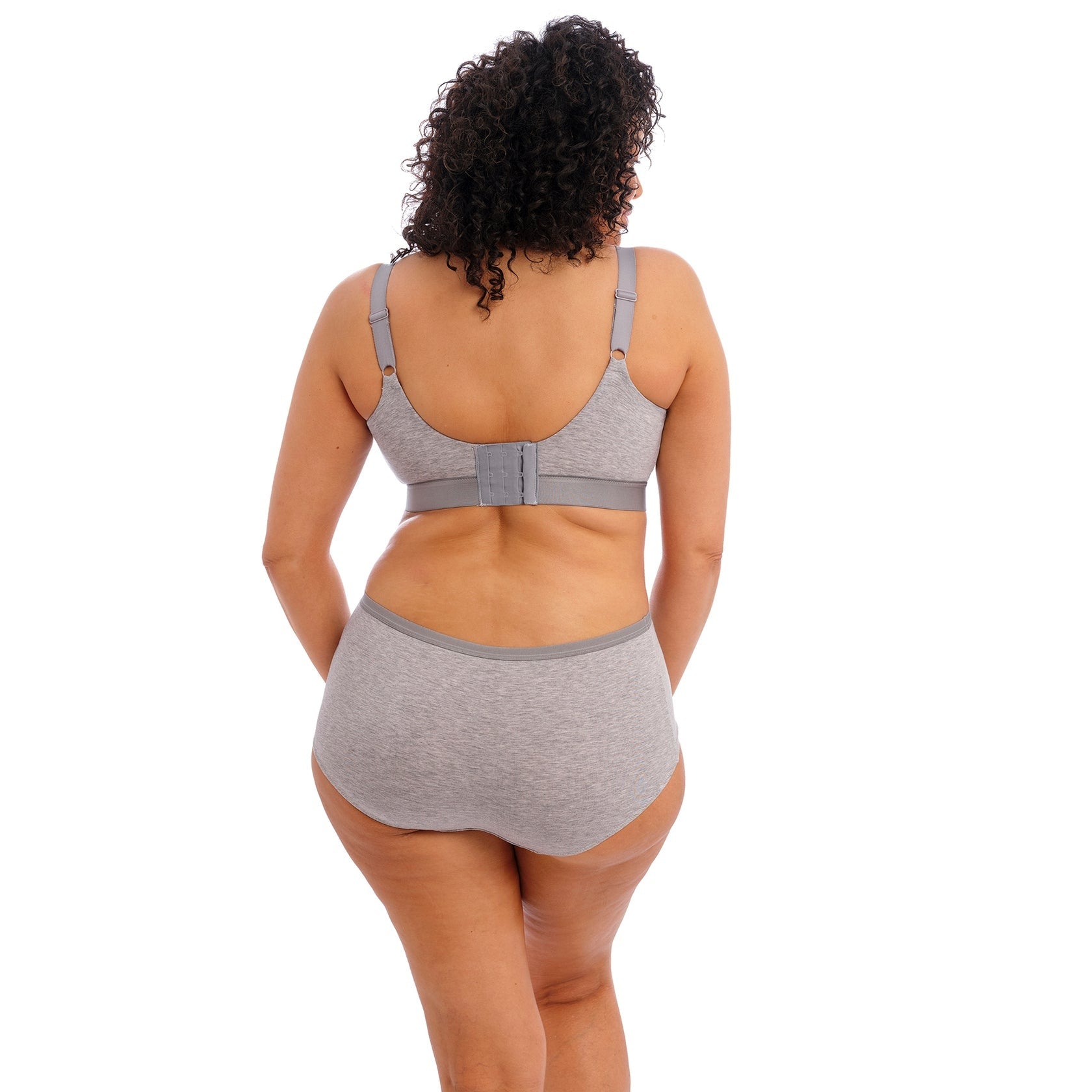 A woman wearing a grey bra and panty set against a white back ground. 