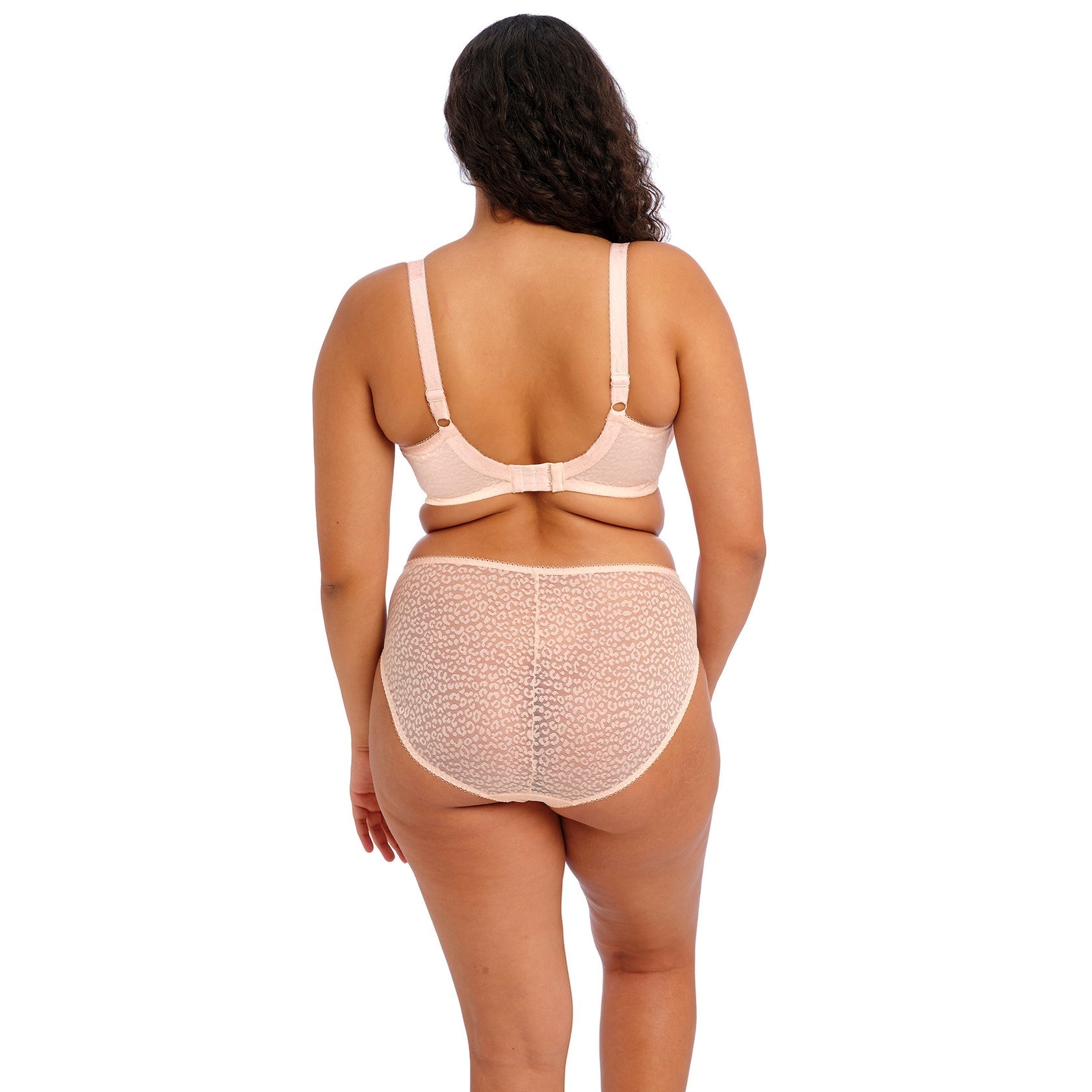 A person wearing a light pink bra and underwear set against a white back ground. 