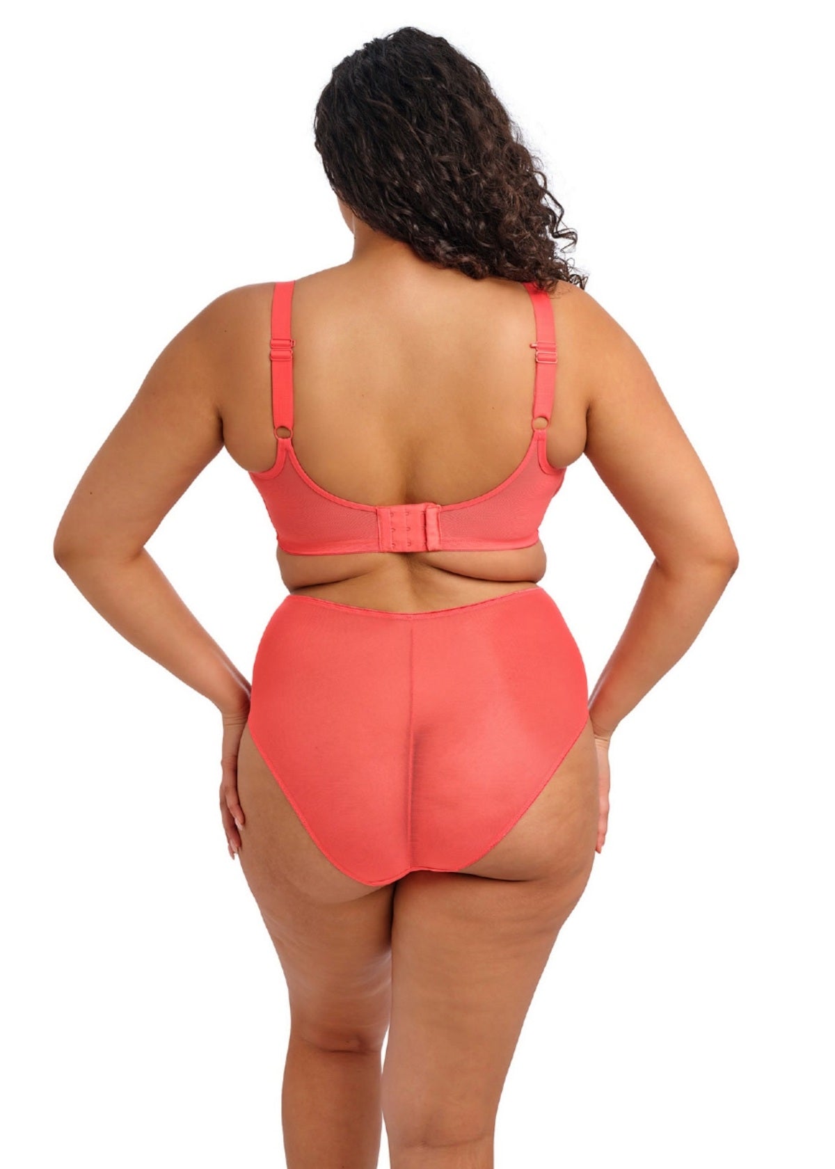 Person wearing a coral bra and panty set standing backward on a white background