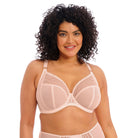 A woman is wearing a beige plunge bra with contemporary bead embroidery. The bra has three-piece cups and side support panels, featuring an elasticated neck edge and moveable J-hook fastening.