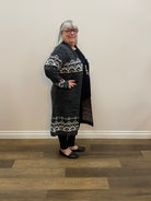 Person wearing a black outfit with white patterns standing on a wooden floor.