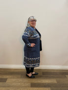Person wearing a blue patterned dress standing against a plain wall.