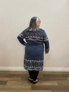 Person wearing a blue patterned sweater standing in room with a brown floor.