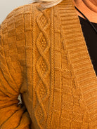 Close-up of a brown knitted sweater with cable pattern.