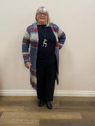 Person wearing a patterned coat standing against a plain wall.