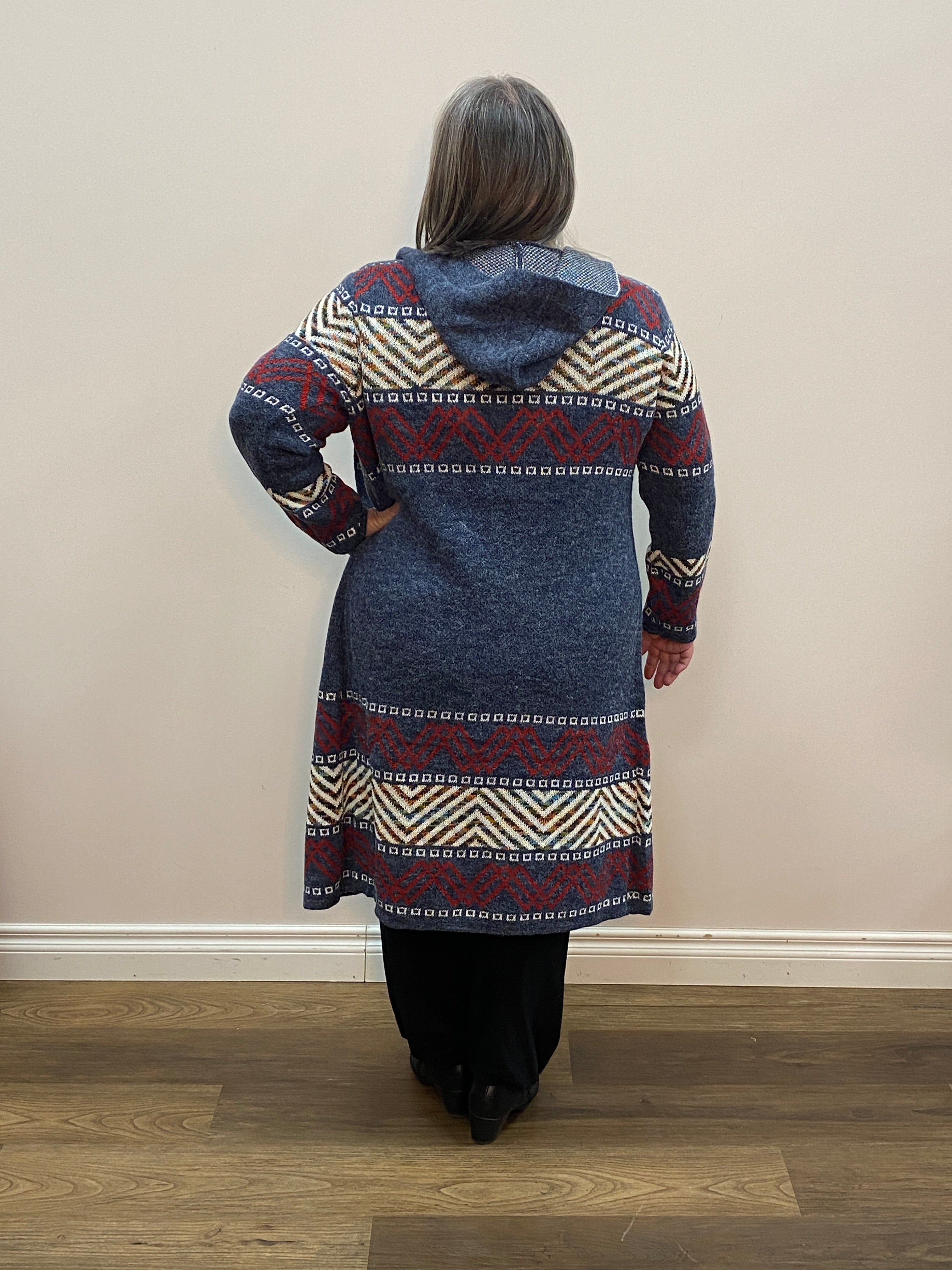 Person wearing a patterned dress standing against a plain wall.