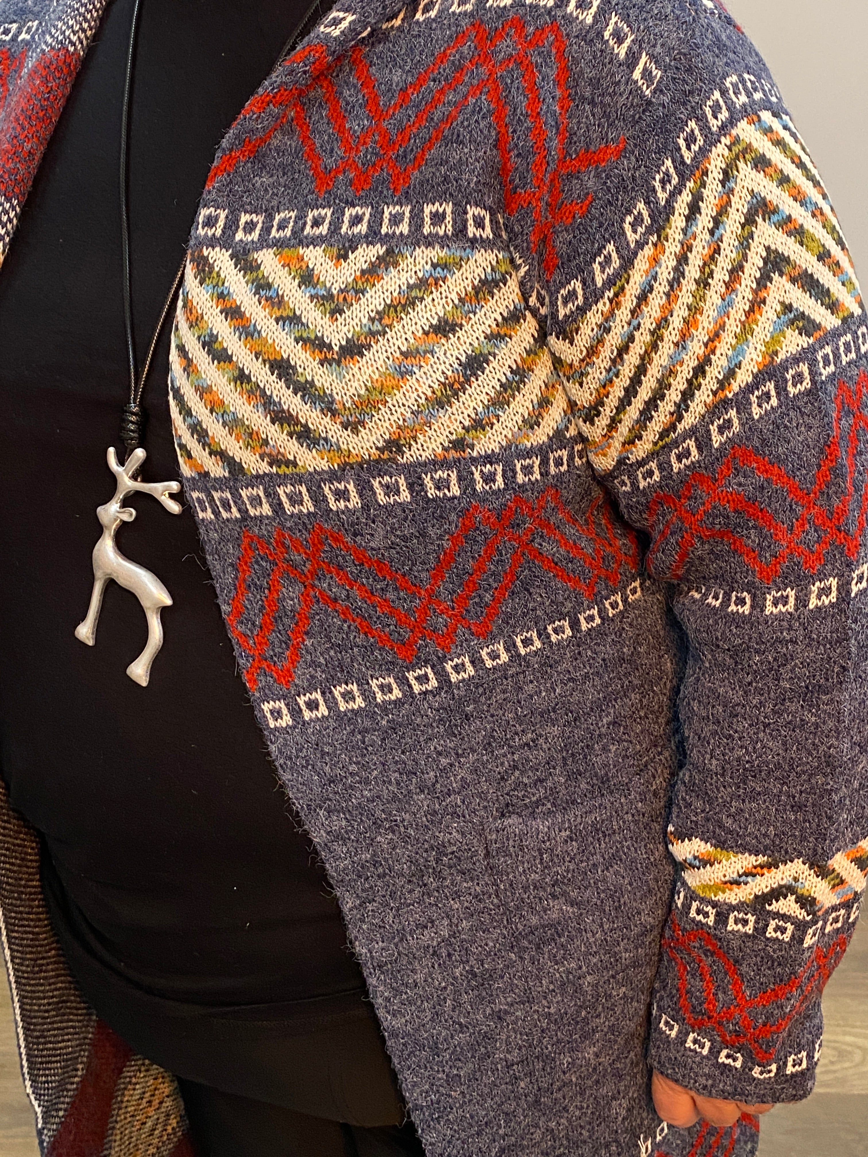 Person wearing a patterned sweater sitting on a chair with a decorative headboard.