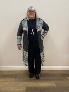 Person wearing a patterned cardigan and black outfit standing on a wooden floor.