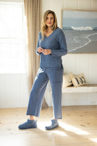 Woman wearing a blue outfit in a bright room with a painting on the wall.