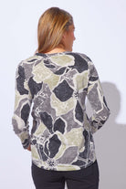Woman wearing a floral patterned long-sleeve top against a plain background