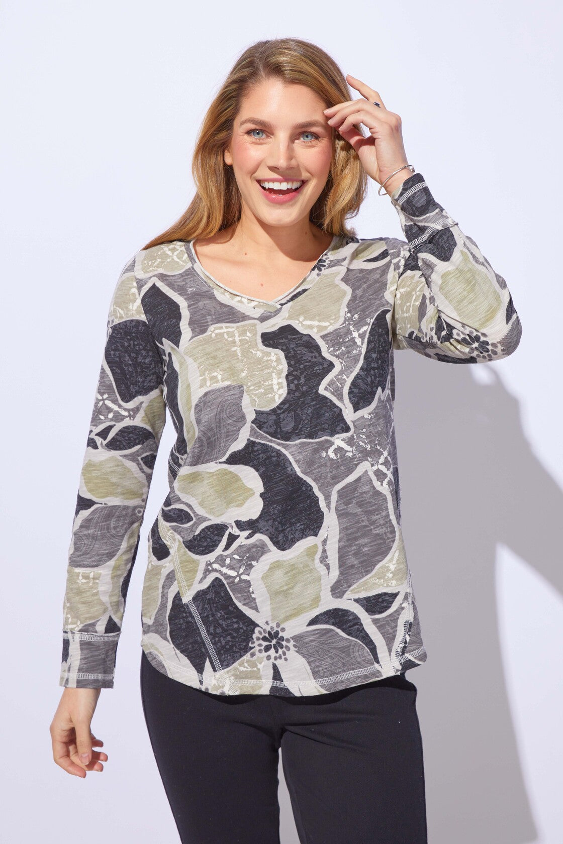 Woman wearing a floral patterned long-sleeve top against a white background
