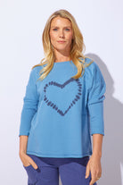 Woman wearing a blue sweater with a heart design on a white background