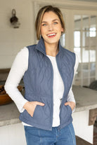 Woman wearing a blue quilted vest in a kitchen setting