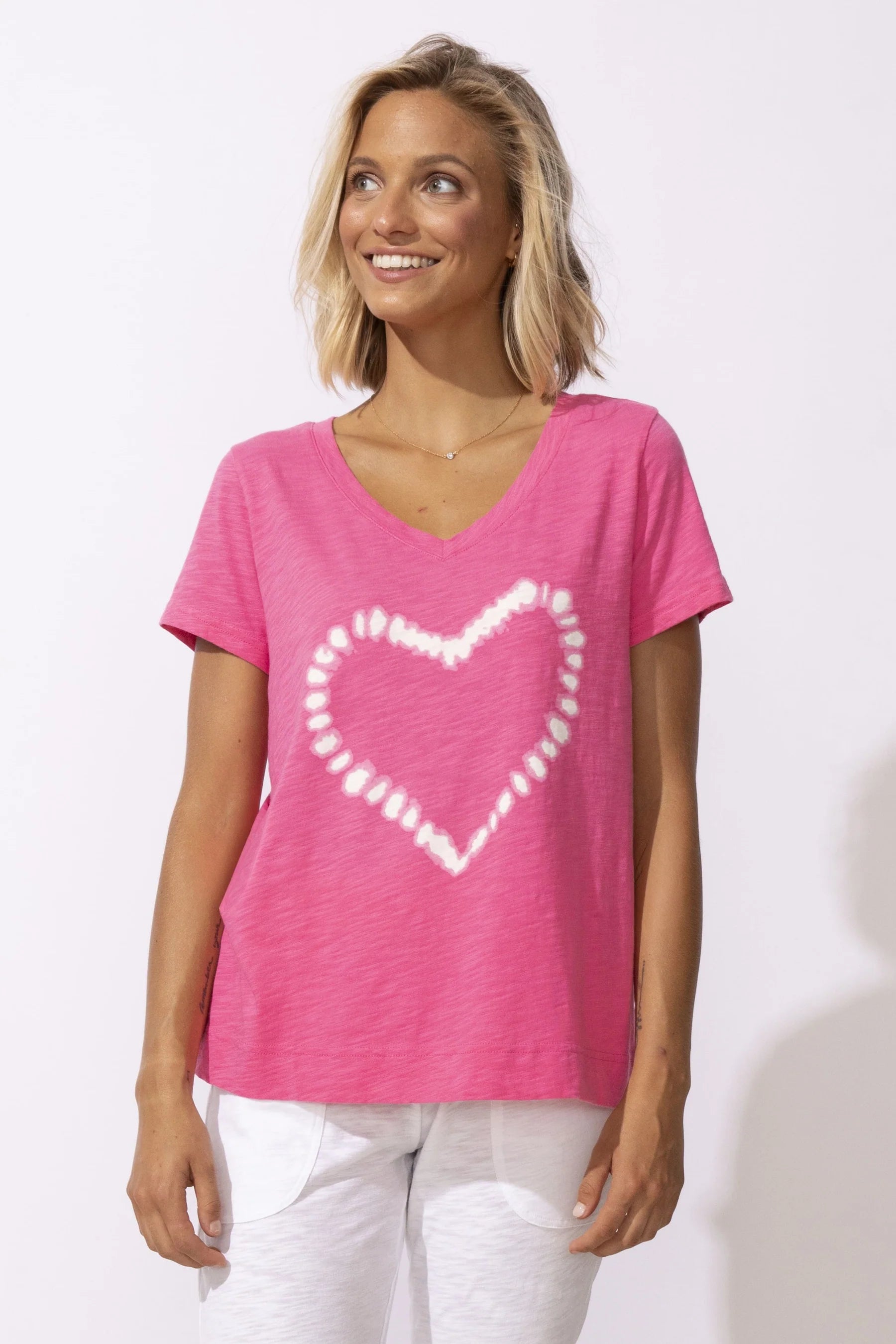 Woman wearing a pink t-shirt with a white heart design on a white background