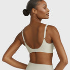 Beyond Bra in Aloe, light sage green wirefree bra on a model from the back view showcasing the adjustable straps and hook and eye back closure. 