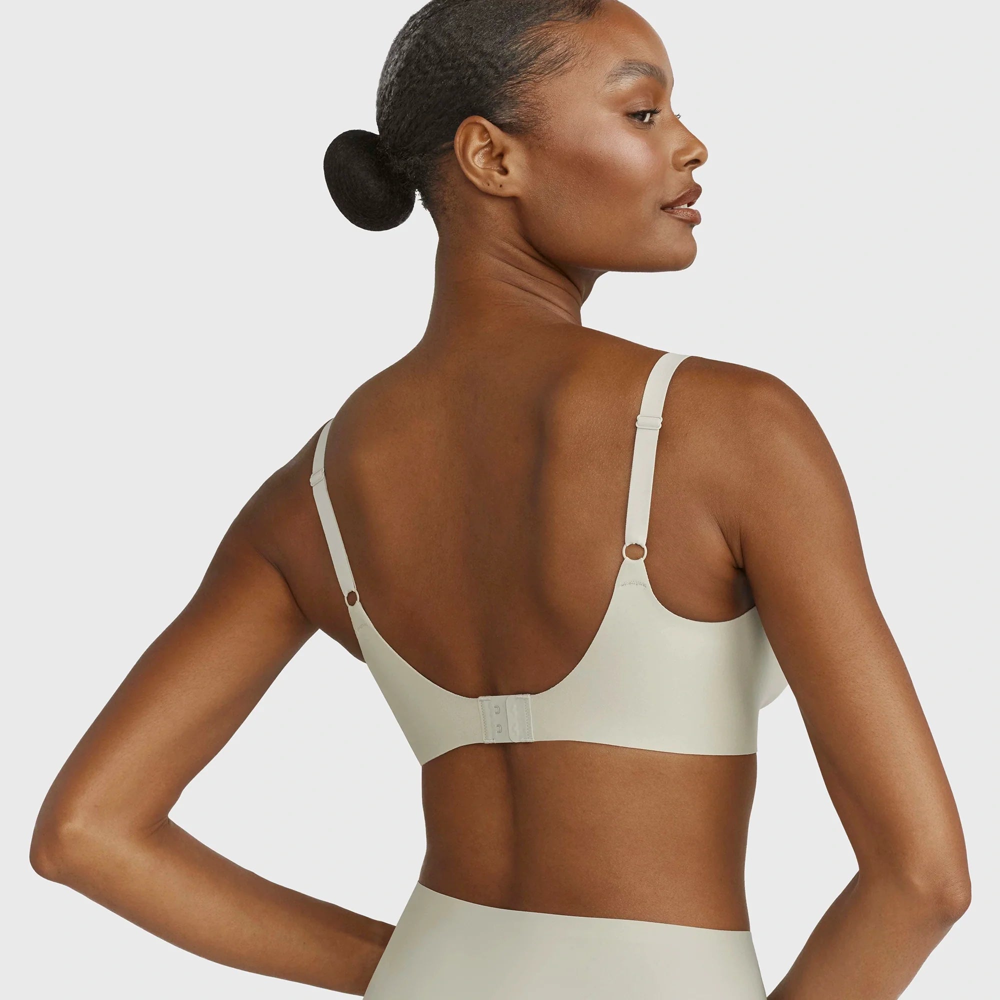 Beyond Bra in Aloe, light sage green wirefree bra on a model from the back view showcasing the adjustable straps and hook and eye back closure. 