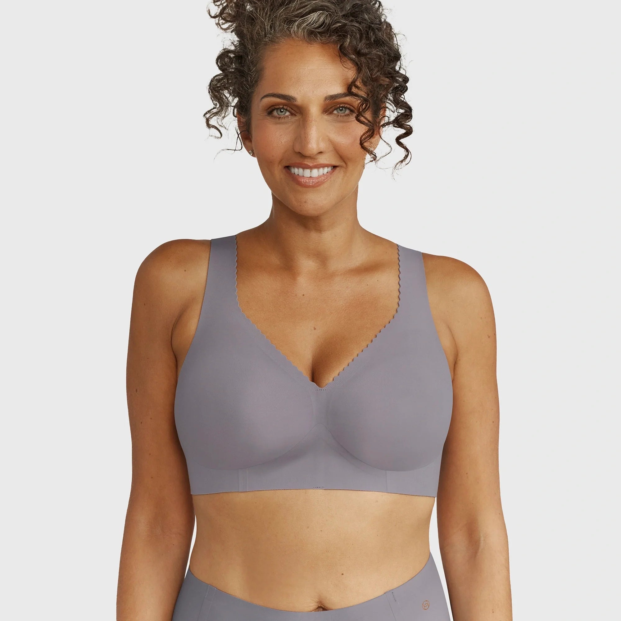Woman wearing the Evelyn & Bobbie Evelyn Bra in London Fog, grey no wire pullover bra, against a white background, front view. 