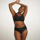 The Beyond Bra in Black, a wirefree bra shown on a model wearing a matching panty from the front view. 
