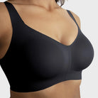 The Beyond Bra in Black, a wirefree bra shown on a model from a close up view of the front of the cups. 