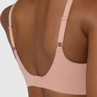 The Beyond Bra in Himalayan Salt, light pinkish neutral wirefree bra shown in a close up view of the back, with close-up detailing of the adjustable straps and hook and eye back closure. 