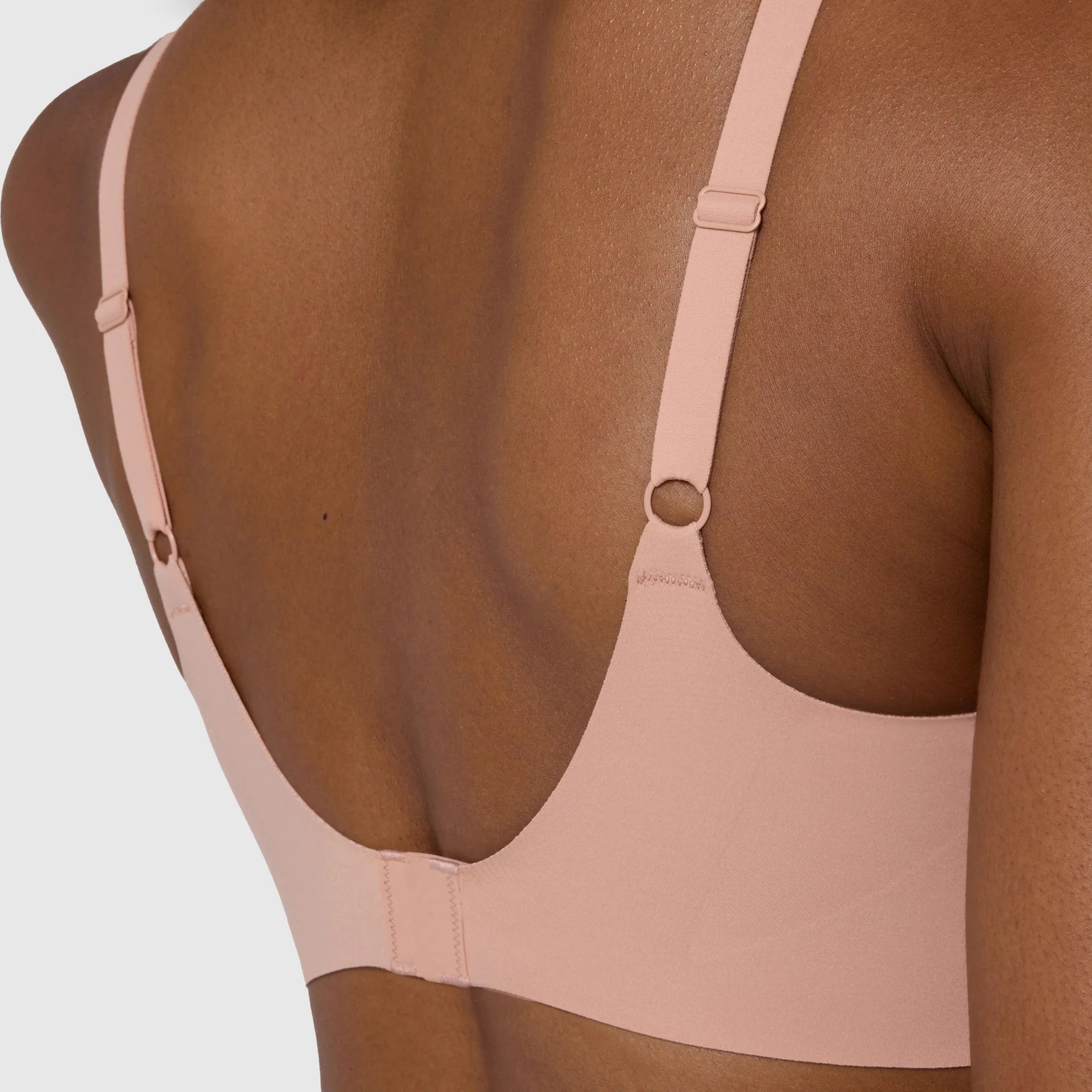 The Beyond Bra in Himalayan Salt, light pinkish neutral wirefree bra shown in a close up view of the back, with close-up detailing of the adjustable straps and hook and eye back closure. 