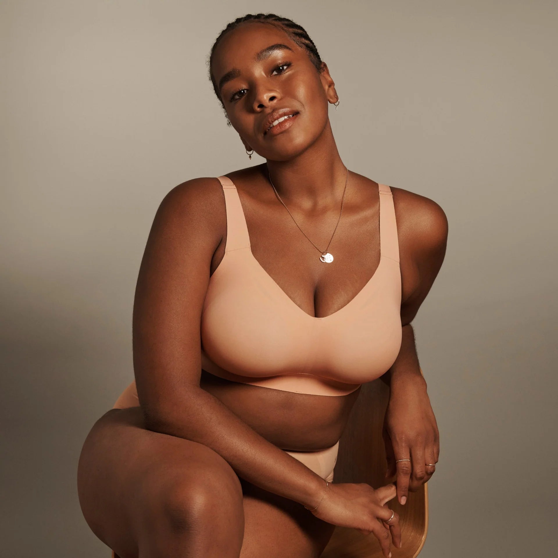 The Beyond Bra in Himalayan Salt shown in a lifestyle image on a model posed on a chair. 
