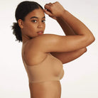 Beyond Bra in Mica, light tan wirefree bra shown on a model with her arms up so you can see the side band view. 