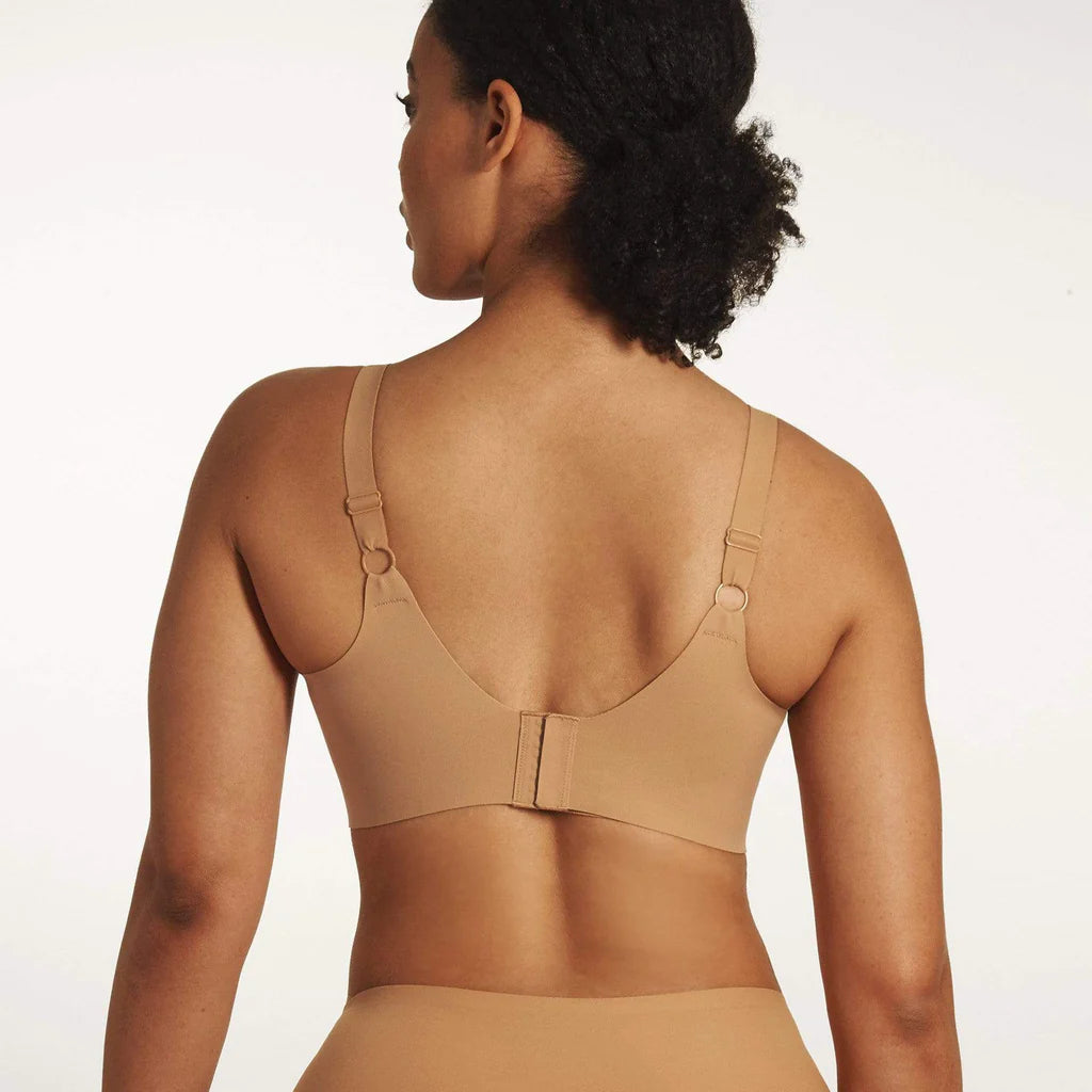 Beyond Bra in Mica, light tan wirefree bra shown on a model from the back view showing the adjustable straps and hook and eye back closure. 