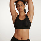 Woman wearing the Evelyn & Bobbie Defy Bra in Black, no wire pullover bra, against a white background, front view. 
