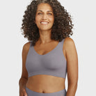 Woman wearing the Evelyn Bobbie Defy Bra in London Fog, light grey no wire bra, on a white background. 