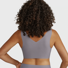 Woman wearing the Evelyn Bobbie Defy Bra in London Fog, light grey no wire bra, on a white background, view of her back smooth band. 