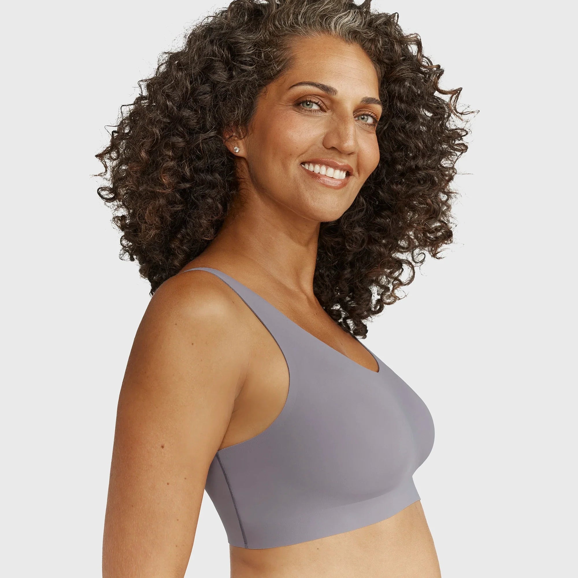 Woman wearing the Evelyn Bobbie Defy Bra in London Fog, light grey no wire bra, on a white background, side view. 