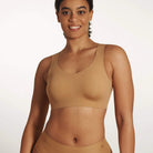 Woman wearing the Evelyn & Bobbie Defy Bra in Mica, light tan no wire pullover bra, against a white background. 