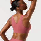 Woman wearing the Evelyn & Bobbie Defy Bra in Pink Canyon, soft pink no wire pullover bra, on a white background. 