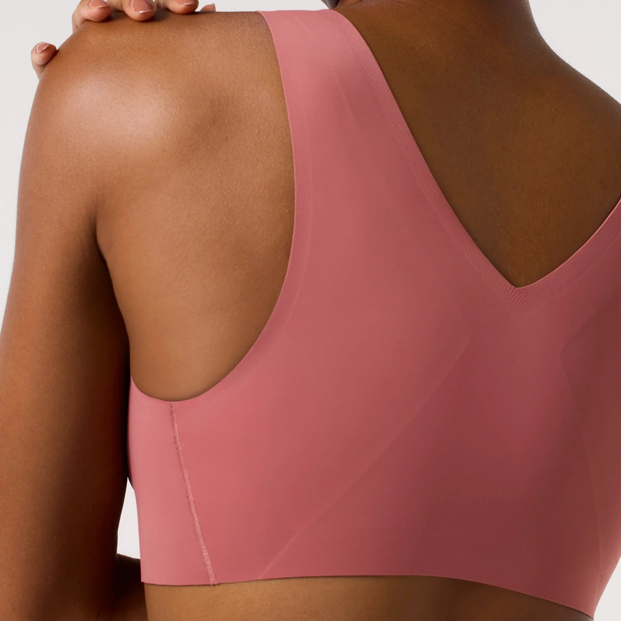 Woman wearing the Evelyn & Bobbie Defy Bra in Pink Canyon, soft pink no wire pullover bra, on a white background. 