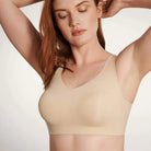 A woman wearing the Evelyn & Bobbie Defy Bra in Sand, light beige no wire bra, on a white background. 