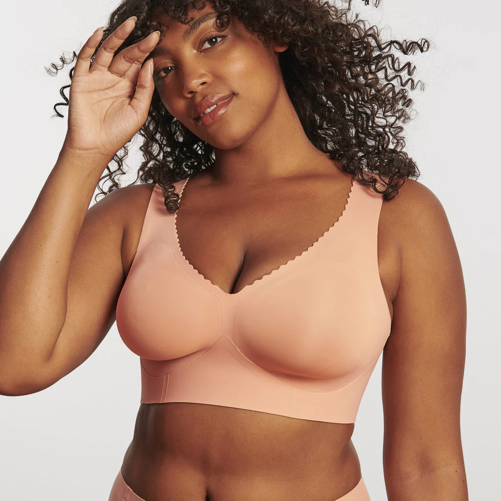 Woman wearing Evelyn & Bobbie Evelyn Bra in Himalayan Salt, light pink no wire pullover bra, against a white background, front view. 
